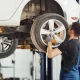 Mechanic in a work uniform changing a car wheel indoors at an auto repair shop
